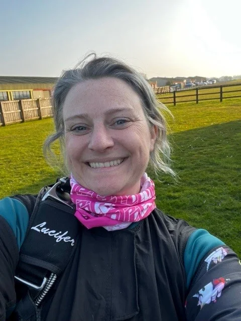 Member spotlight portrait: a skydiver geared up and grinning at the drop zone